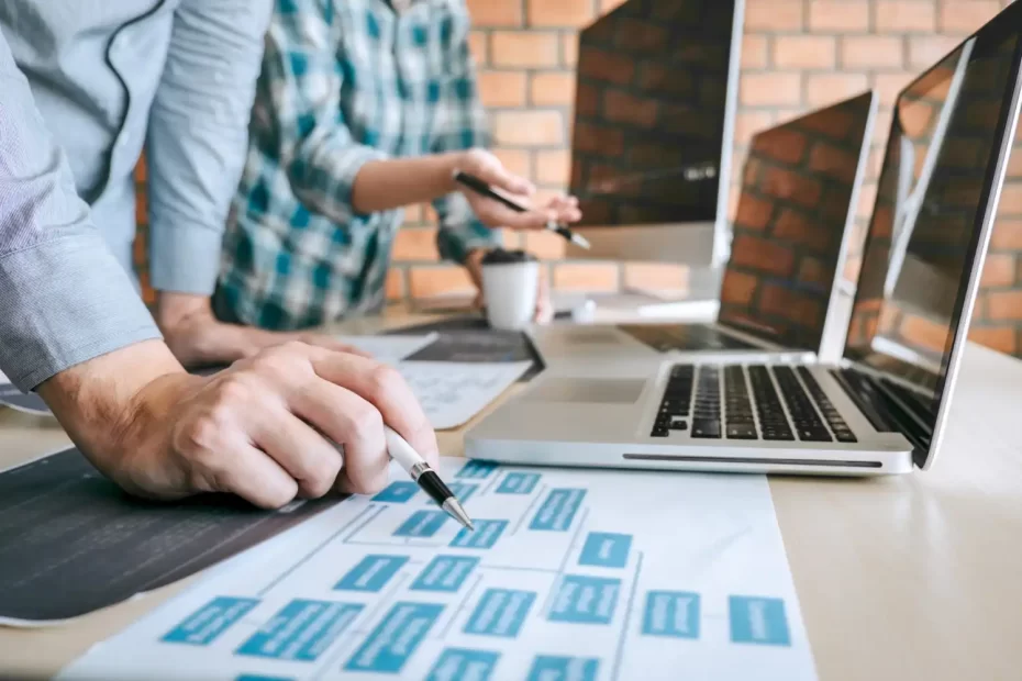 Imagem de uma equipe analisando estratégias para melhorar a conversão de um blog técnico, com laptops e materiais de trabalho na mesa.