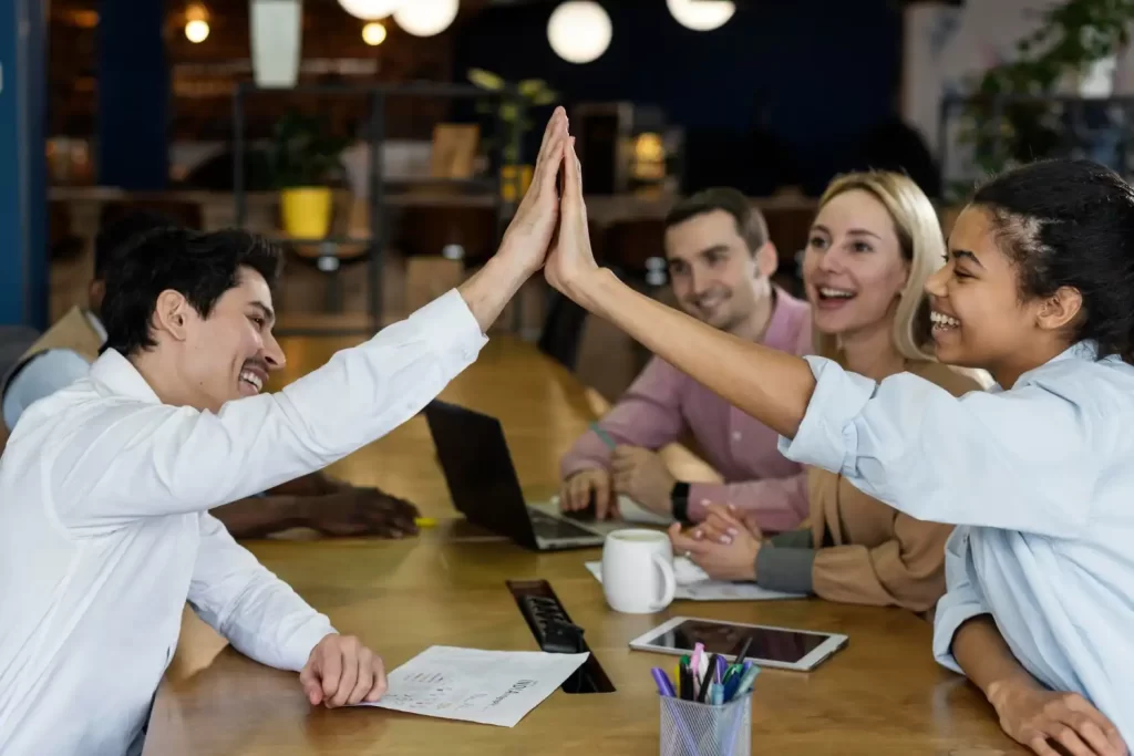 Jovens profissionais da Geração Z celebrando uma conquista no ambiente de trabalho, simbolizando a nova liderança e as mudanças com o comando da geração Z.